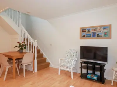 a living room with a television and a table and chairs at Acorns in Falmouth
