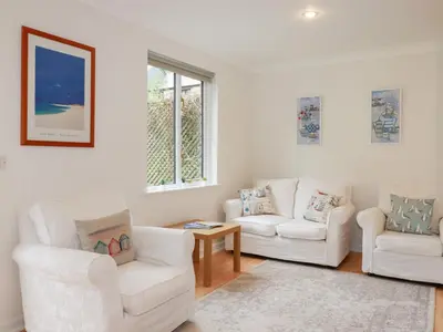 a living room with two white chairs and a table at Acorns in Falmouth