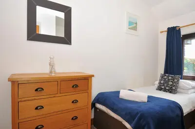 a bedroom with a bed and a dresser and a mirror at Norvys in Tintagel
