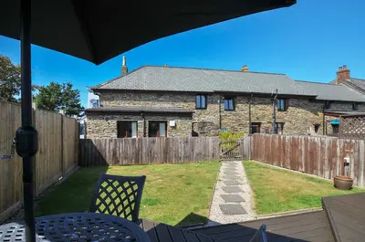 a yard with a stone house with a wooden fence at Norvys in Tintagel