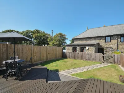 a patio with a table and an umbrella on a deck at Norvys in Tintagel