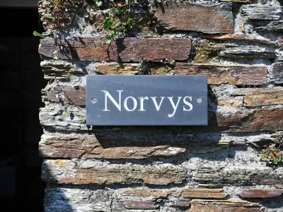 a sign on the side of a brick wall at Norvys in Tintagel