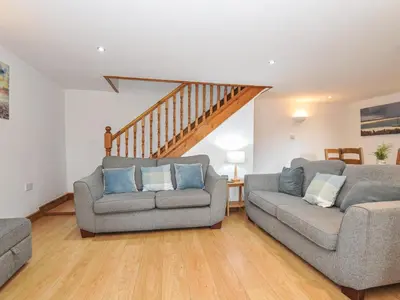 a living room with two couches and a staircase at Norvys in Tintagel