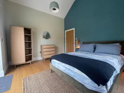 a bedroom with a large bed and a green wall at Parc an Praze - Cornwall Retreat by the Sea in Perranuthnoe