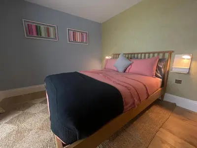 a bedroom with a large bed with pink pillows at Parc an Praze - Cornwall Retreat by the Sea in Perranuthnoe