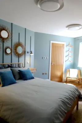 a bedroom with a large bed with blue walls at Chymaen - Magnificent Cornish coastal home in Marazion