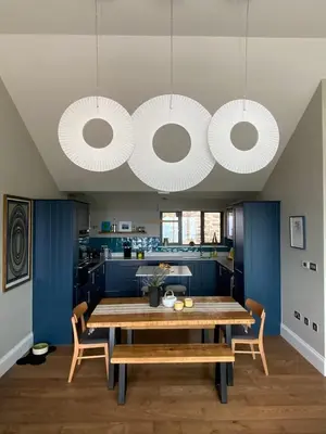 a dining room with a wooden table and blue cabinets at Chymaen - Magnificent Cornish coastal home in Marazion