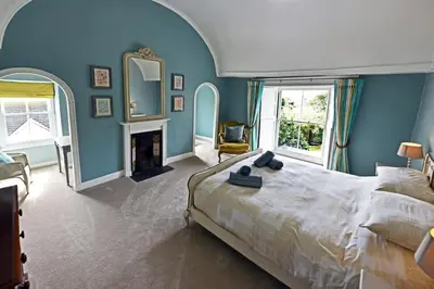a bedroom with a large bed and blue walls at Historical Churchtown House Cornwall in Perranuthnoe
