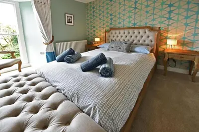 a bedroom with a large bed with blue pillows on it at Historical Churchtown House Cornwall in Perranuthnoe