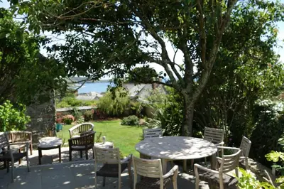 a table and chairs in a yard with a tree at Historical Churchtown House Cornwall in Perranuthnoe
