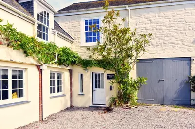 a white brick house with a blue garage at Historical Churchtown House Cornwall in Perranuthnoe