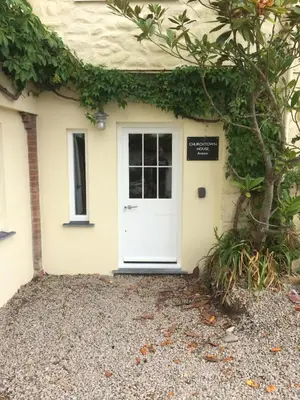 a white door of a house with a sign on it at Historical Churchtown House Cornwall in Perranuthnoe