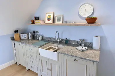 a kitchen with a sink and a clock on the wall at Historical Churchtown House Cornwall in Perranuthnoe