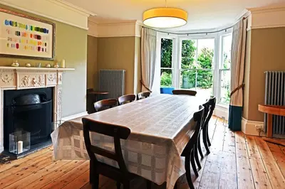 a dining room with a table and chairs and a fireplace at Historical Churchtown House Cornwall in Perranuthnoe