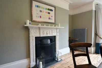 a living room with a fireplace and a chair at Historical Churchtown House Cornwall in Perranuthnoe