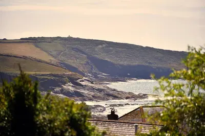 a view of the ocean with a hill in the background at Grade II Listed 17th-Century Rectory in Cornwall in Perranuthnoe