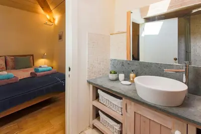 a bathroom with a sink and a bedroom with a bed at Stunning Old Carthouse with seaview in Penzance