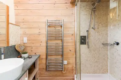 a bathroom with wooden walls and a shower and a sink at Stunning Old Carthouse with seaview in Penzance