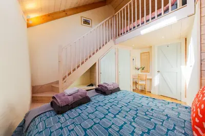 a bedroom with a bed and a stair case at Stunning Old Carthouse with seaview in Penzance