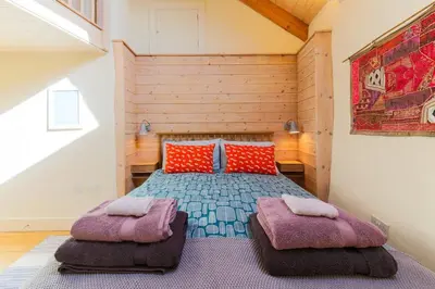 a bedroom with a bed with two ottomans at Stunning Old Carthouse with seaview in Penzance