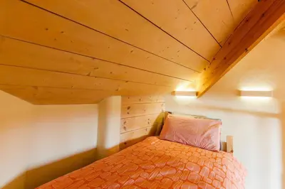 a bed in a room with a wooden ceiling at Stunning Old Carthouse with seaview in Penzance