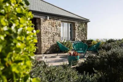 a patio with green chairs and a building at Stunning Old Carthouse with seaview in Penzance