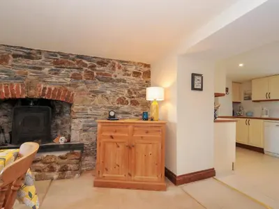 a living room with a stone wall with a fireplace at Rosewin Farmhouse in Wadebridge