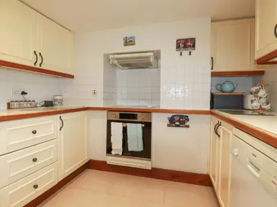 a kitchen with white cabinets and an oven at Rosewin Farmhouse in Wadebridge