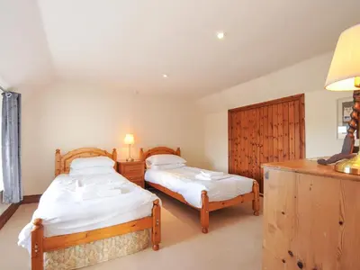 a bedroom with two beds and a desk with a lamp at Rosewin Farmhouse in Wadebridge