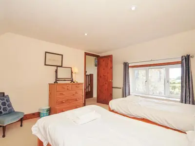 a bedroom with two beds and a window at Rosewin Farmhouse in Wadebridge