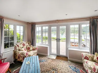 a living room with a couch and chairs and windows at Point House in Saint Just in Roseland