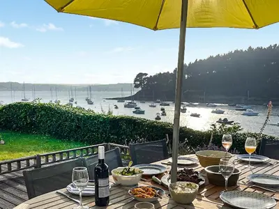 a wooden table with wine glasses and food and a view of a harbor at Point House in Saint Just in Roseland