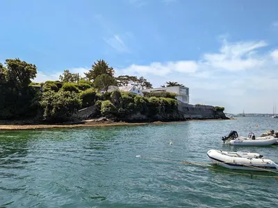 two boats floating in the water near an island at Point House in Saint Just in Roseland