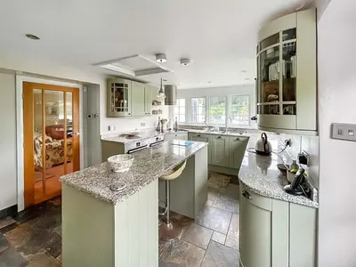 a kitchen with green cabinets and marble counter tops at Point House in Saint Just in Roseland
