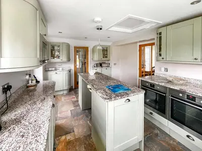 a kitchen with white cabinets and granite counter tops at Point House in Saint Just in Roseland