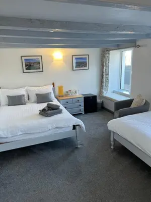 a bedroom with two beds and a chair and a window at The Fourways Inn in Saint Minver