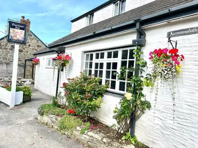a white building with flowers on the side of it at The Fourways Inn in Saint Minver