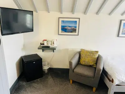 a bedroom with a chair and a tv on the wall at The Fourways Inn in Saint Minver