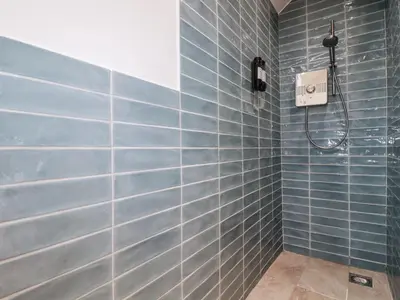 a bathroom with blue tiled walls and a shower at The Old Dairy in Bodmin
