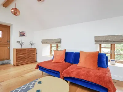 a living room with a blue couch with orange pillows at The Old Dairy in Bodmin