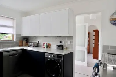 a kitchen with white cabinets and a dishwasher at Sleeps 9- KingBeds- FamilyFriendly- ContactlessCI in Wadebridge