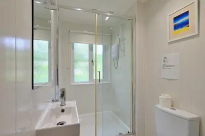 a white bathroom with a shower and a sink at Finest Retreats - Joyful Cottage in St Ives