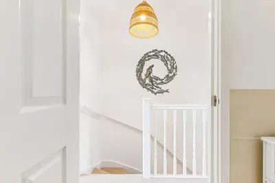 a hallway with a white staircase with a light fixture at Offshore, Coastal retreat, set in the heart of Charlestown in Charlestown