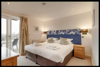 a bedroom with a large bed with a blue headboard at Tallyn House 202 in Saint Columb Major