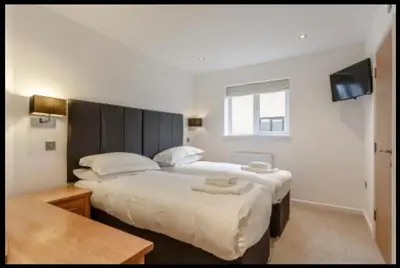 a hotel room with two beds and a television at Tallyn House 202 in Saint Columb Major