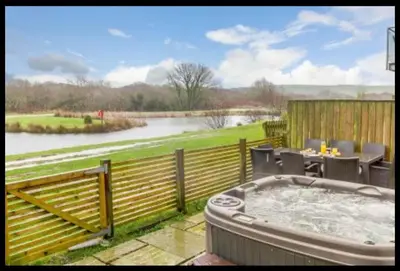 a hot tub on a deck with a view of a river at Tallyn House 202 in Saint Columb Major
