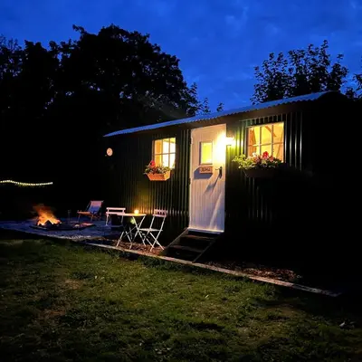 a tiny house with a picnic table and a fire at Harpers Huts in Lanivet