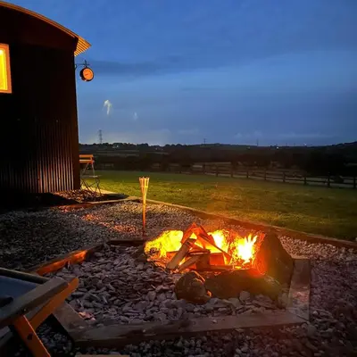 a fire pit in a yard next to a building at Harpers Huts in Lanivet
