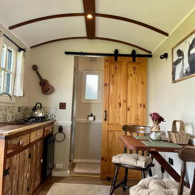 a kitchen with a wooden door and a table at Harpers Huts in Lanivet