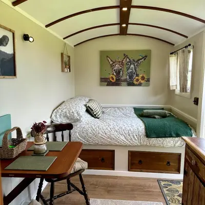 a bedroom with a bed and a desk and a table at Harpers Huts in Lanivet